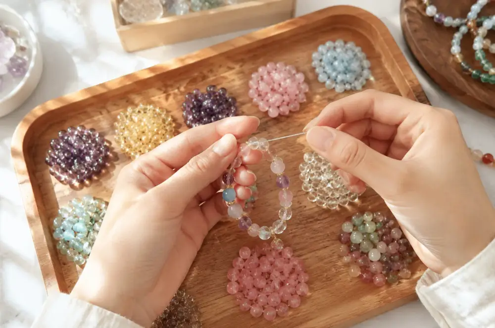 Hands stringing a crystal bracelet over a bead tray